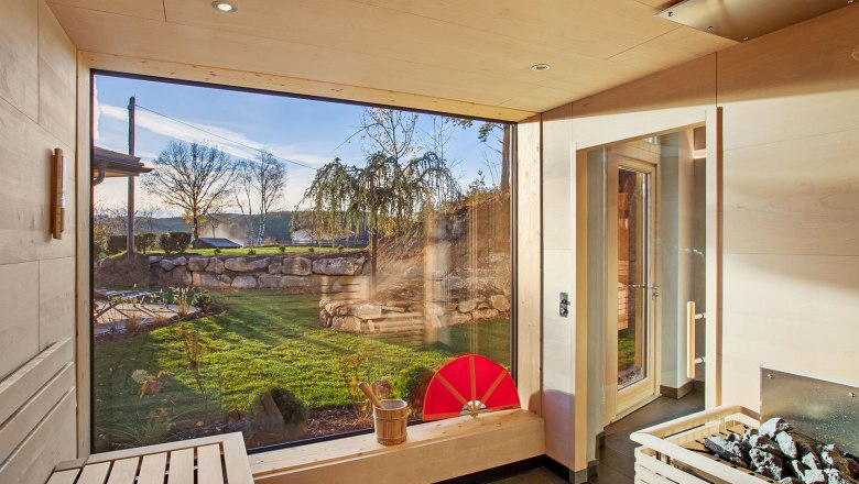 Panoramasauna, © Gesundheitshotel Klosterberg GmbH Innenansicht einer modernen Sauna mit großem Fenster und Blick auf einen Garten.