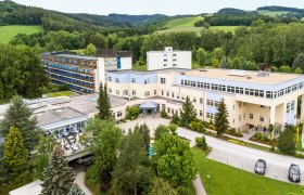 Luftaufnahme, © Gesundheitsresort Königsberg Luftaufnahme eines großen Gebäudekomplexes in einer grünen Landschaft.