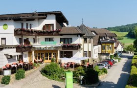 Außenansicht des VitalZeit Hotel Weber mit Terrasse und Blumen.