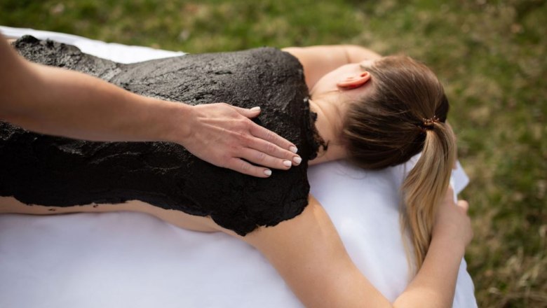 Person erhält eine Moorpackung auf dem Rücken im Freien.