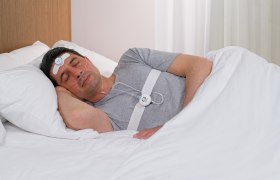 Mann schläft mit Schlafüberwachungsgerät im Bett.