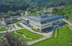 Luftaufnahme eines modernen Gebäudes mit Garten und umliegender Landschaft.