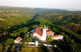 Luftaufnahme des Klosters Pernegg umgeben von Waldlandschaft.