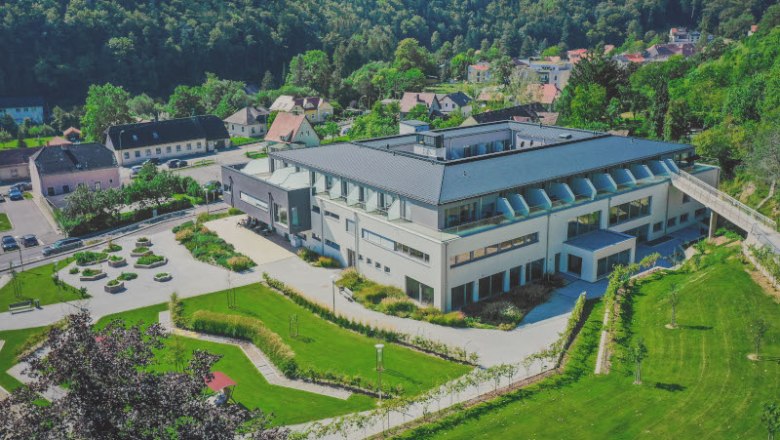 Luftaufnahme eines modernen Gebäudes mit Garten und umliegender Landschaft.