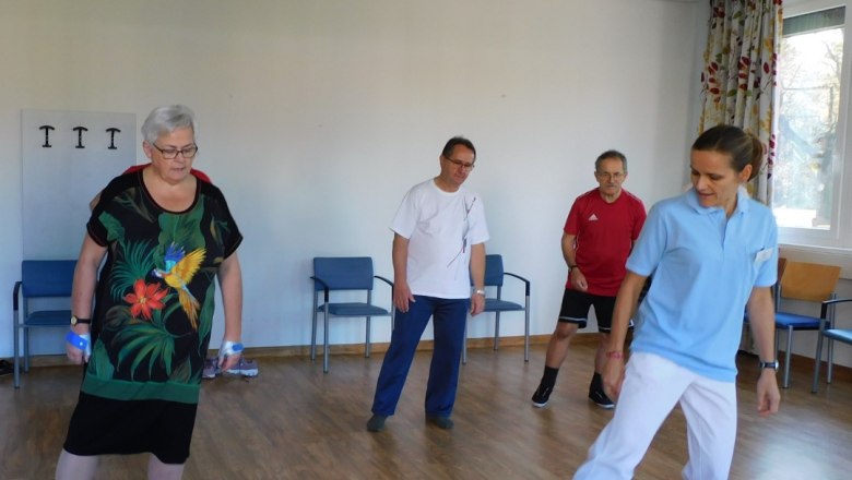 Gruppe von Menschen tanzt in einem Raum mit Holzboden.