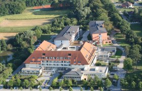 Luftaufnahme der Klinik Pirawarth mit roten Dächern, umgeben von Bäumen und Feldern.