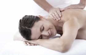 Frau erhält eine Rückenmassage und lächelt entspannt.