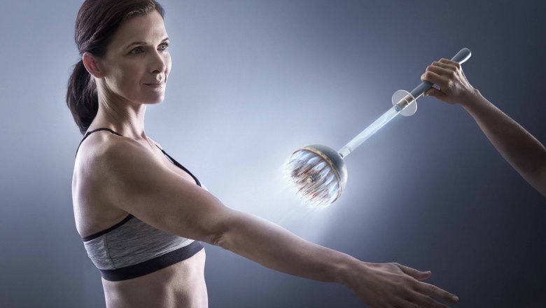 Eine Frau erhält eine Arsonvalisation-Behandlung am Arm mit einem leuchtenden Gerät.